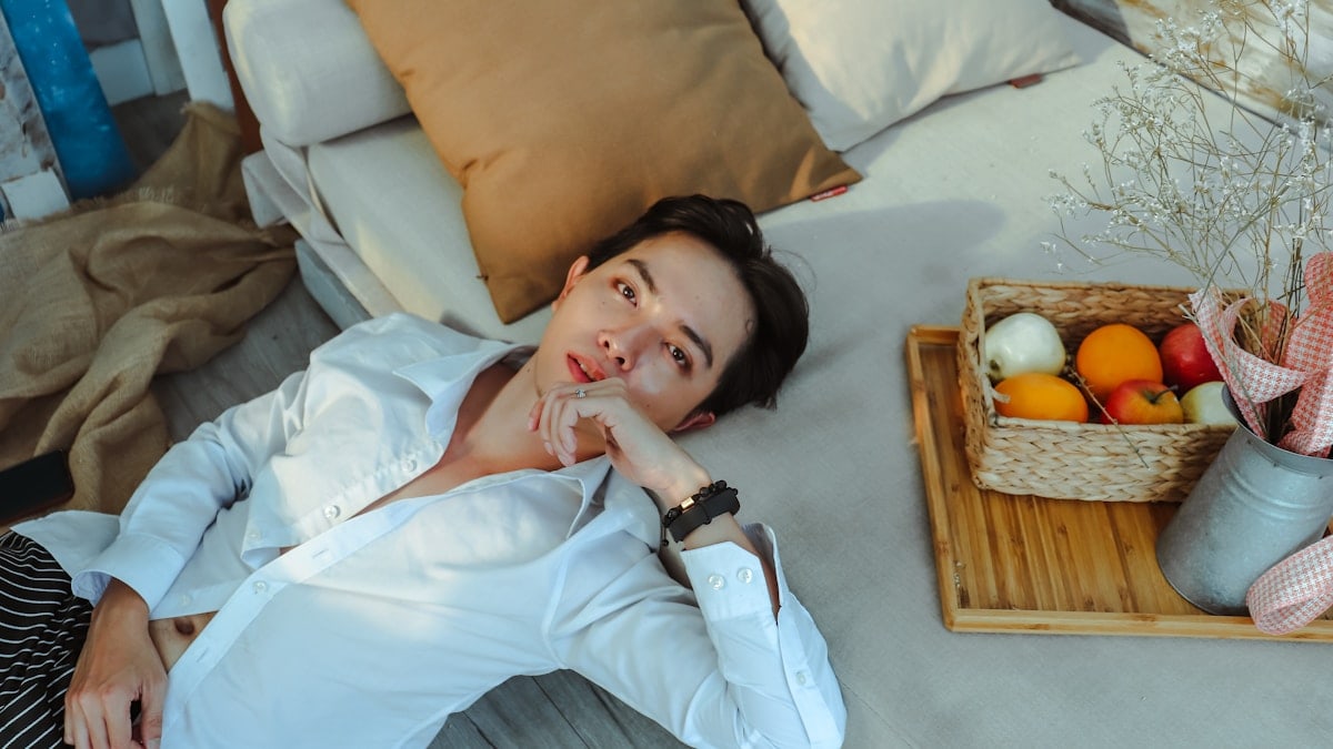 a man laying on a bed next to a basket of fruit
