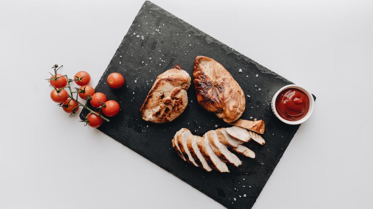 Grilled chicken served on slate with tomatoes and ketchup, a delicious still life.