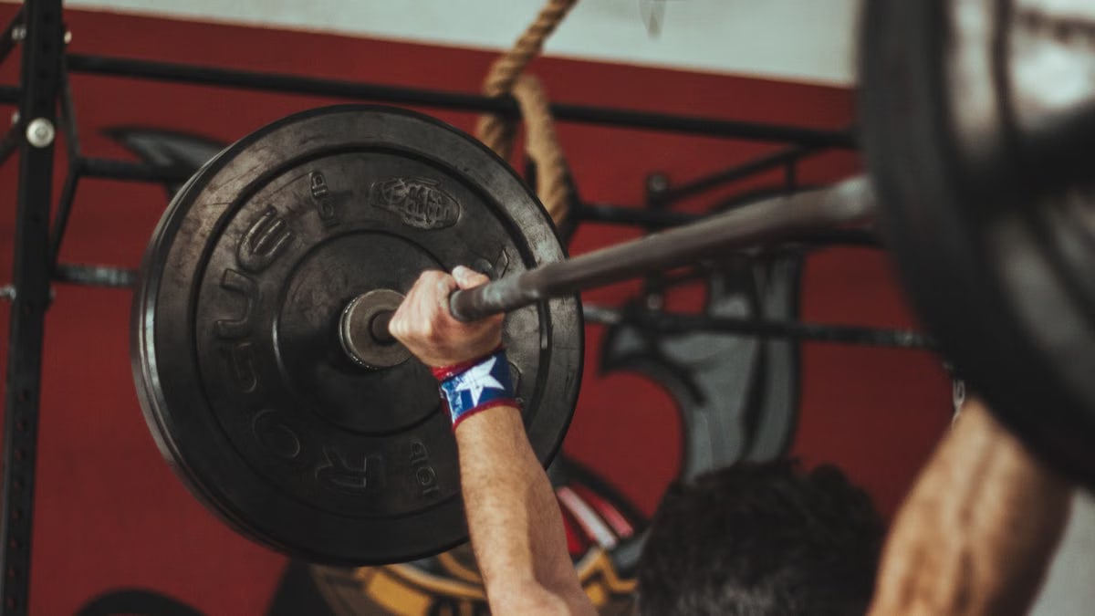 Athlete lifting heavy barbell during strength training session in gym.